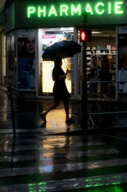 le rôle des pharmaciens / a woman walking down a street holding an umbrella