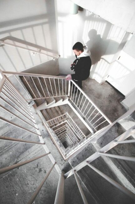 le validisme / Man walking down a modern staircase in an urban building with striking geometrical patterns.