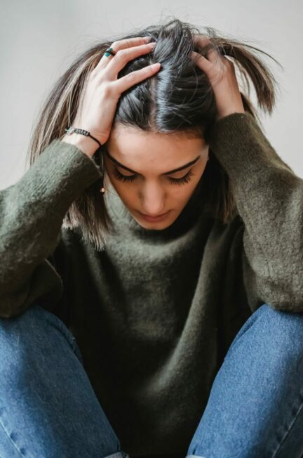 troubles cognitifs - Desperate female in casual clothes touching head while sitting near white wall with bent legs in light room at home