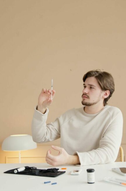 diabète / A young man holds a syringe while preparing an insulin injection in a medical setting.